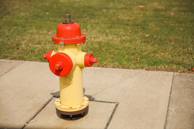 Żółty i czerwony hydrant przeciwpożarowy stoi na chodniku.