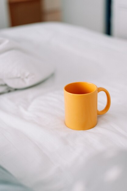 Żółty kubek do kawy w białym łóżku
