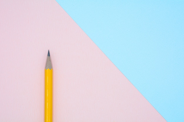 Żółty ołówek na niebieskim i różowym papierze