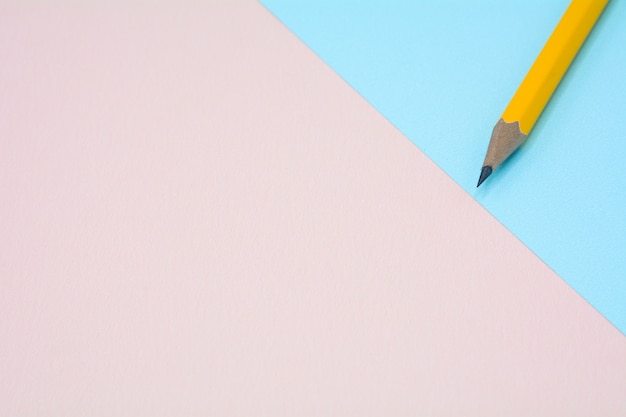 żółty ołówek na niebieskim i różowym tle papieru