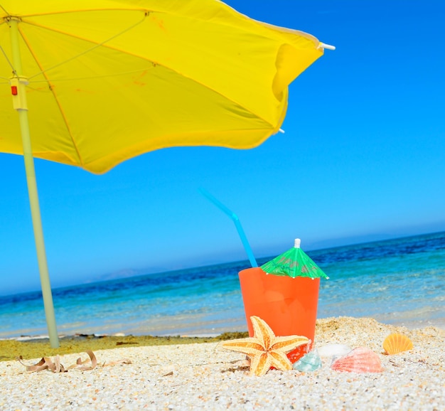 Żółty parasol i pomarańczowy napój przy pochylonym brzegu