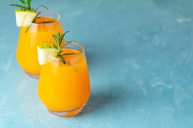 Żółty pomarańczowy koktajl z melonem i miętą w szkle na niebieskim betonowym tle z bliska Letnie napoje i koktajle alkoholowe Koktajl alkoholowy lub detoksykacyjny