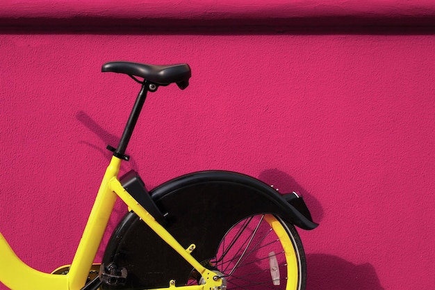 Żółty rower w pobliżu różowej ściany