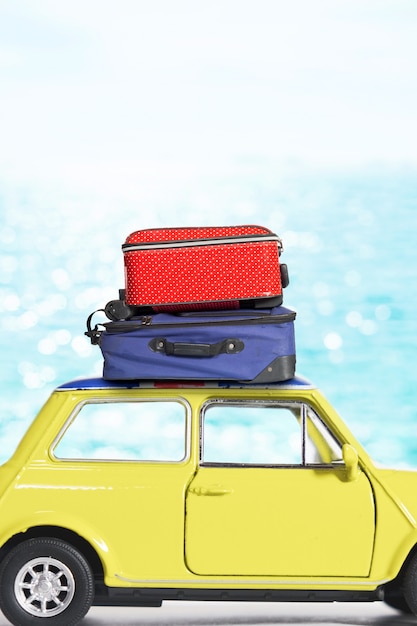 Żółty samochód z torby podróżne na dachu na plaży.