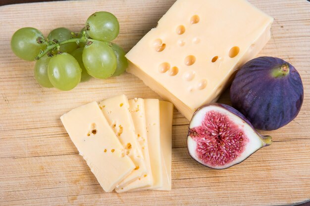 Żółty ser i świeże figi na drewnianej desce do krojenia