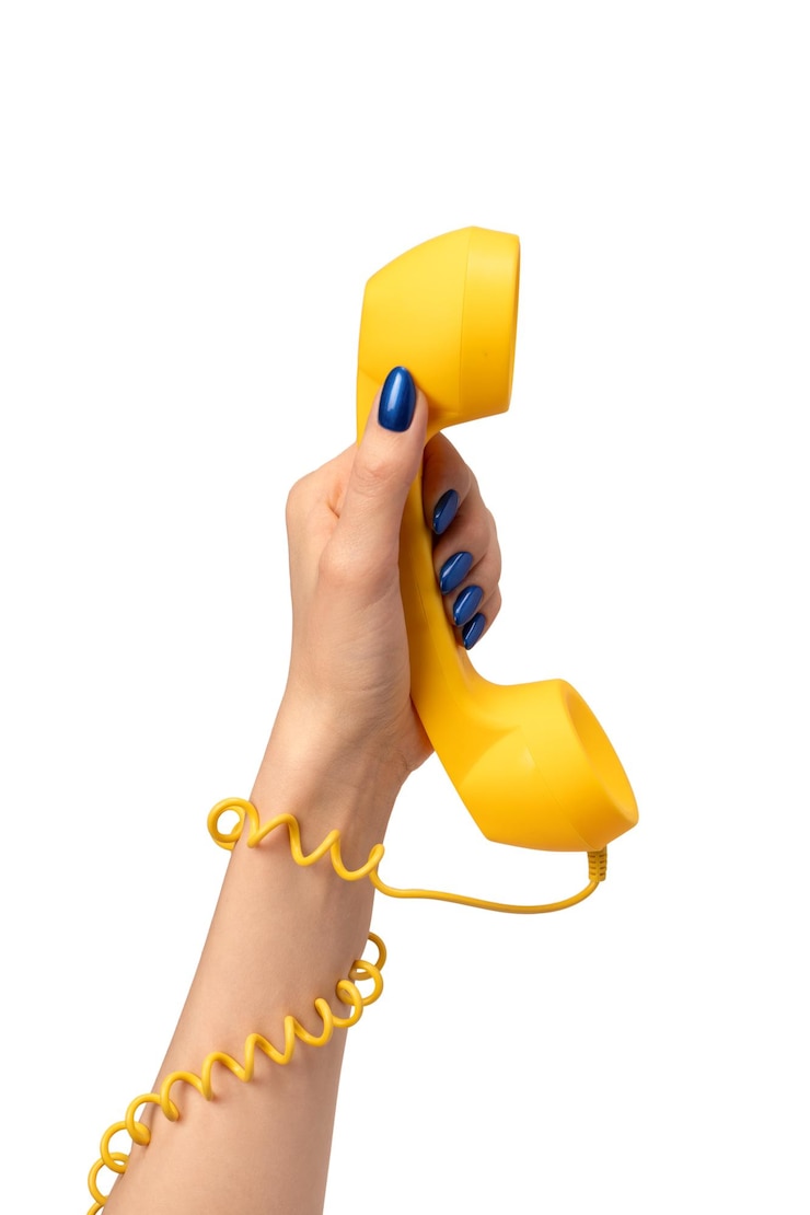 Zdjęcie żółty telefon w ręce kobiety izolowany na białym przestrzeni kopiowania