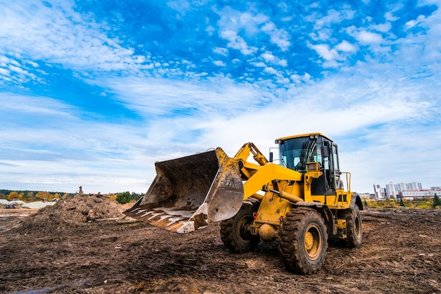 Zdjęcie Żółty traktor wyrównuje grunt pod nowy dom w budowie