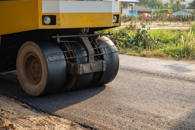 Żółty walec parowy lub zagęszczarka gleby pracująca na autostradzie asfaltowej na placu budowy