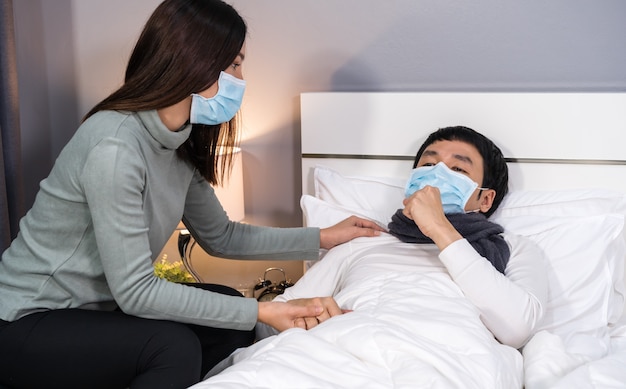 Żona Opiekuje Się Chorym Mężem Na łóżku W Domu, Ludzie Muszą Nosić Maskę Medyczną Chroniącą Przed Pandemią Koronawirusa