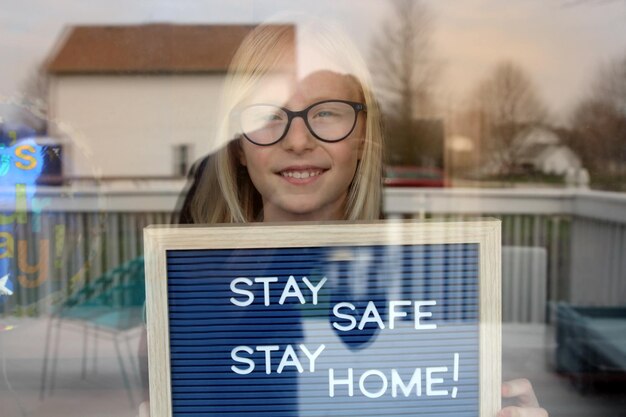 Zdjęcie zostań w domu kwarantanna zapobieganie pandemii koronawirusa piękna dziewczyna pozostaje w pobliżu otwartego okna