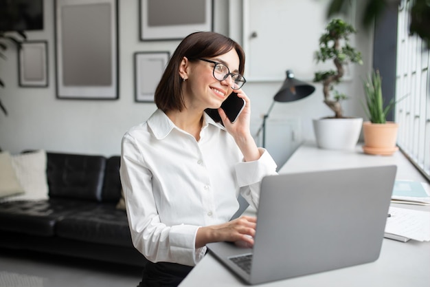 Zrelaksowana bizneswoman rozmawia przez telefon komórkowy Uśmiechnięta kobieta prowadzi przyjemną rozmowę przez telefon komórkowy