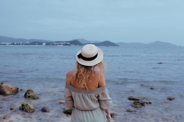 Zrelaksowana kobieta cieszy się ocean zatokę, wolność i życie przy piękną plażową linią brzegową przy wietrzną chmurną pogodą. Młoda dama czuje się wolna, zrelaksowana i szczęśliwa. Pojęcie wakacji, wolności, szczęścia, przyjemności