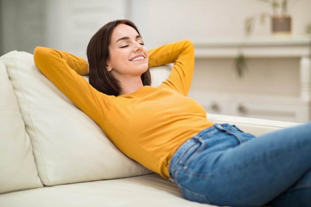 Zrelaksowana młoda kobieta chłodzi się na kanapie w domu