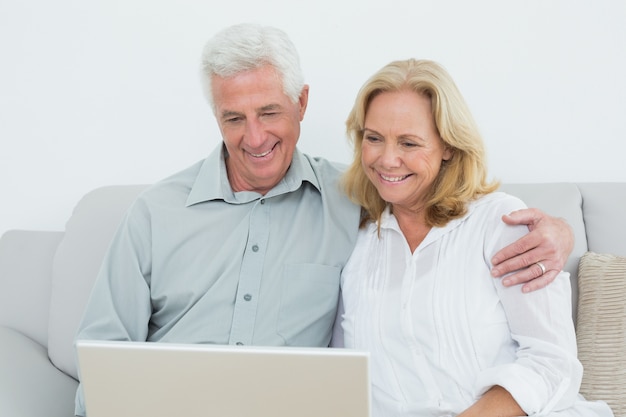 Zrelaksowana starsza para używa laptop w domu