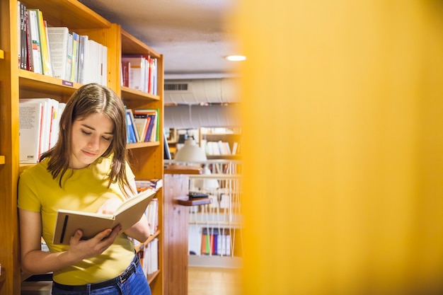 Zdjęcie zrelaksowanej nastolatka czytelnicza książka w bibliotece