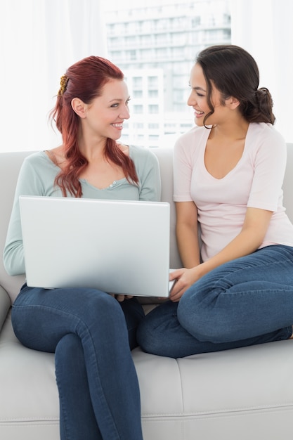 Zrelaksowani żeńscy przyjaciele używa laptop w domu