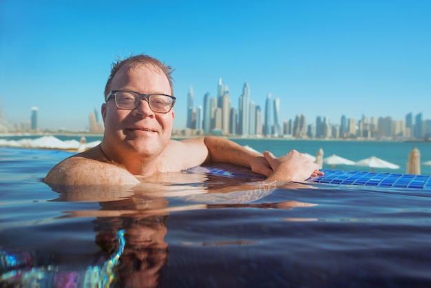 zrelaksowany rudy mężczyzna z Europy kaukaskiej na basenie w Dubaju