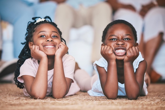Zrelaksuj się dziewczyny lub portret szczęśliwych dzieci na podłodze, dywanie lub macie, łącząc się lub bawiąc się razem w domu rodzinnym Śmieszne dzieci lub twarze rodzeństwa afrykańskich dzieci uwielbiają odpoczywać lub cieszyć się wakacjami
