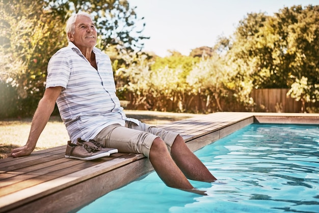 Zrelaksuj się na emeryturze i myśl ze starcem przy basenie oraz na letni spokój i szczęście Uśmiechnij się spokojnie i na wakacjach z seniorem z nogami w wodzie na przerwie na szczęśliwe wakacje i zabawę