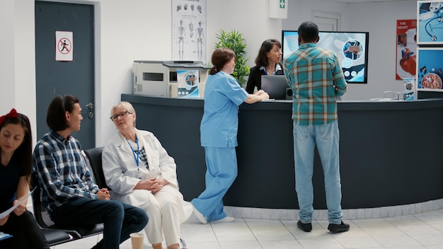 Zróżnicowana grupa pacjentów siedzących w poczekalni, aby zarejestrować się na wizytę, oczekujących na rozpoczęcie konsultacji w recepcji szpitala. Chorzy w holu kliniki, aby zrobić wizytę kontrolną.
