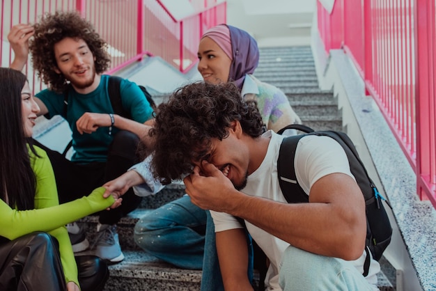 Zróżnicowana grupa uczniów siedzi na schodach nowoczesnego korytarza szkolnego podczas przerwy edukacyjnej