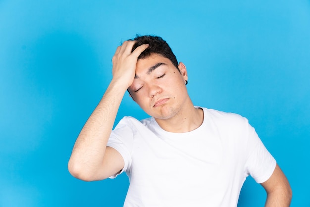 Zrozpaczony nastolatek latynoski chłopiec na białym tle na niebieskim tle Koncepcja stresu lękowego i depresji