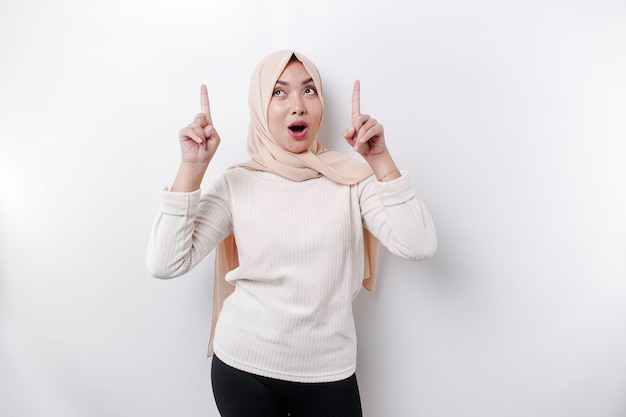 Zszokowana azjatycka muzułmanka w chustce na głowie, wskazująca na miejsce kopiowania na niej odizolowane białym tłem