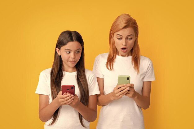 Zszokowana kobieta i dziewczyna czatują online z aplikacją do robienia blogów rodzinnych