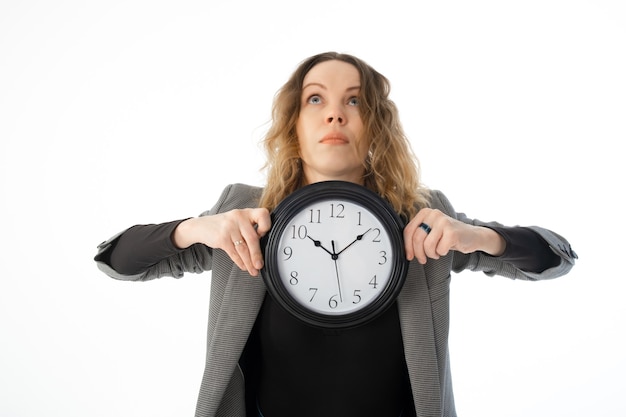 Zdjęcie zszokowana kobieta trzyma w dłoniach duży zegar na białym tle