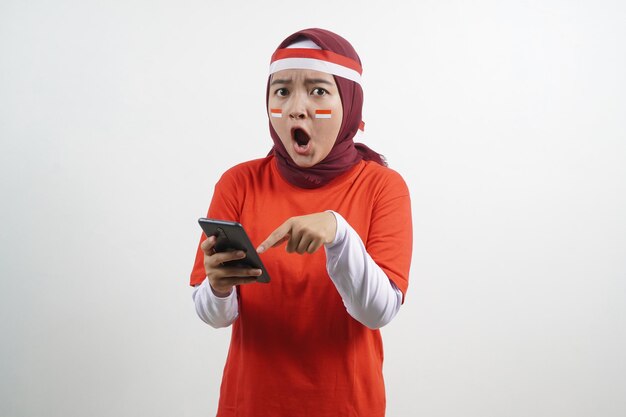 Zdjęcie zszokowana kobieta trzymająca smartfona indonezyjskiego dnia niepodległości