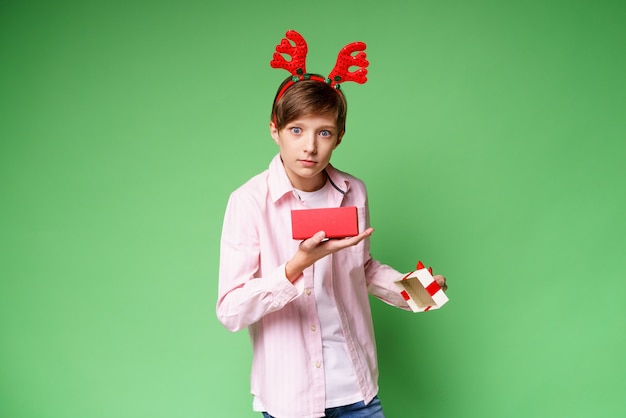 Zszokowany facet z rogami jelenia trzymający pudełko na zielonym tle kopia przestrzeń zaskoczony chłopiec w różowym ...