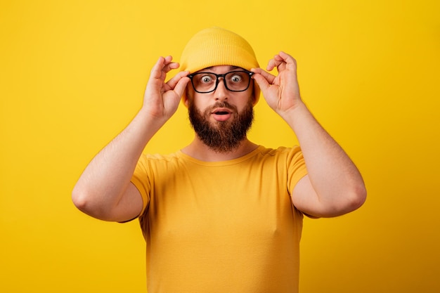 Zszokowany mężczyzna w okularach na żółtym tle, wow imotion
