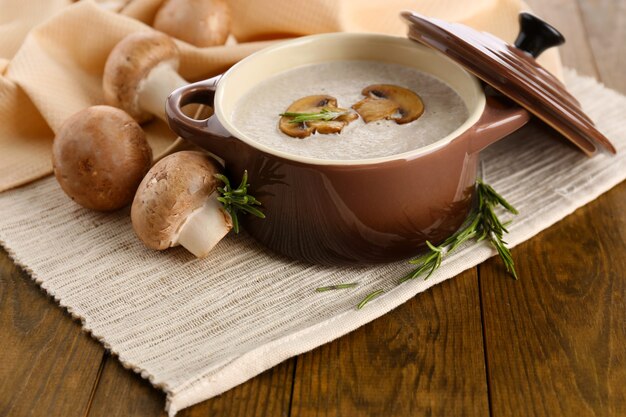 Zupa grzybowa w garnku, na drewnianym stole