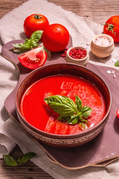 Zupa pomidorowa z bazylią w misce. Dojrzałe warzywa, świeże warzywa, pachnące przyprawy. Vintage drewniany stół, z bliska