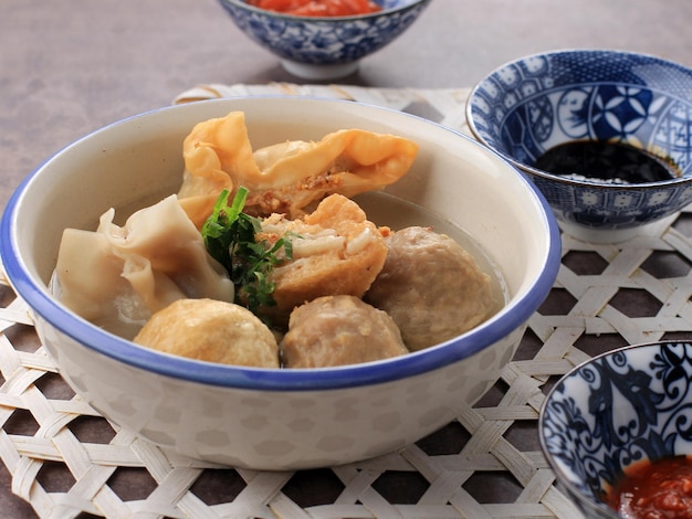 Zupa z klopsikami Bakso Malang z różnymi dodatkami, takimi jak Shiumay smażony z tofu lub Bakso Goreng, podawana na stole z sosem sojowym Sambal i sosem pomidorowym Wybrane Focus