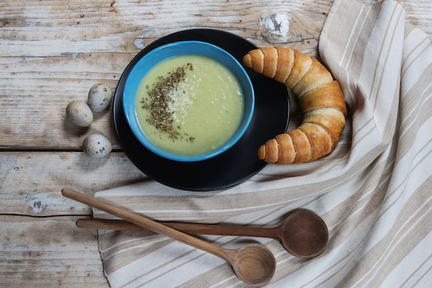 Zupa z puree z warzyw w talerzu na stole i chlebie, drewnianych łyżkach i ręczniku