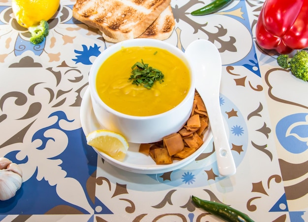 Zupa z soczewicą z łyżką krakersów z cytryną i chlebem podawany w garnku odizolowanym na stole widok arabskiego jedzenia
