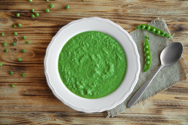 Zdjęcie zupa z zielonego groszku w talerzu na drewnianym stole