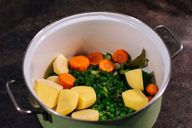 Zupa ze świeżych warzyw w garnku Wegetariańska zupa jarzynowa z ziemniakami zielony groszek marchew