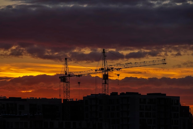 Żurawie wieżowe nad wieżowcami nowy budynek na tle zachodu słońca Budowa budynków mieszkalnych