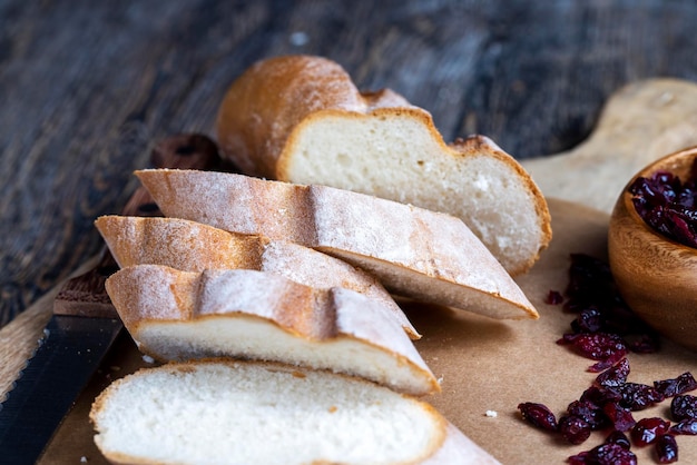 Żurawina i pokrojona miękka świeża bagietka na desce do krojenia i stole