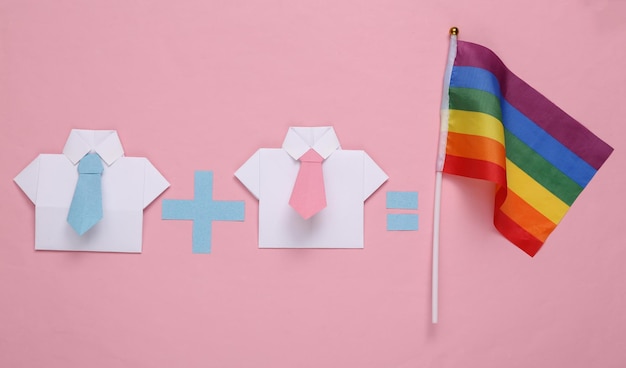 Zdjęcie związki gejów lgbt równanie z dwoma męskimi koszulkami origami i tęczową flagą na różowym tle