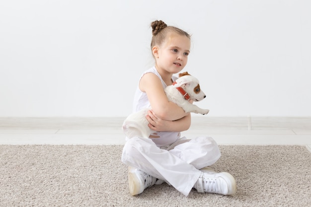 Zwierzęta i koncepcja zwierząt - dziewczynka bawi się ze szczeniakiem Jack Russell Terrier
