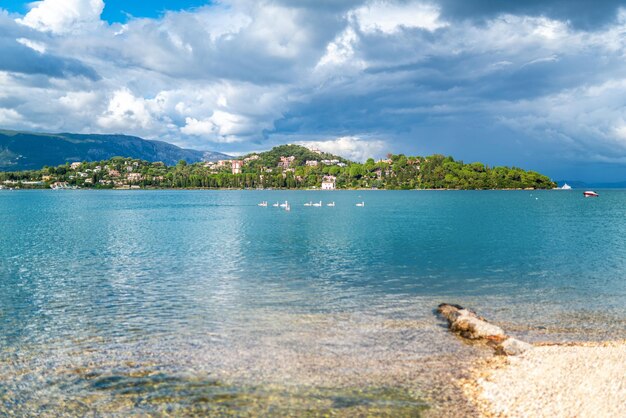 Żwirowa plaża w zatoce Morza Śródziemnego na tle wyspy Korfu