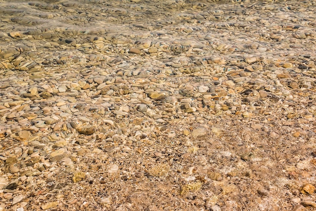 Żwirowa plaża z lazurową wodą morską tekstury tła Kamienny wzór pod wodą w piękny słoneczny letni dzień