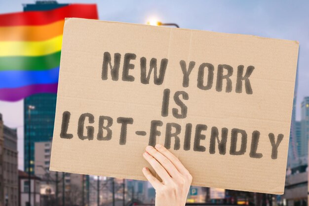 Zwrot New York is LGBTFriendly na banerze w męskiej dłoni z zamazaną flagą LGBT