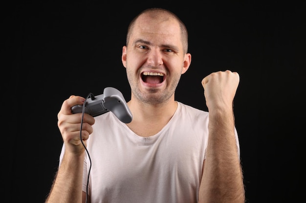 Zwycięska gra wideo Emocjonalny mężczyzna z gamepadem na czarnym tle