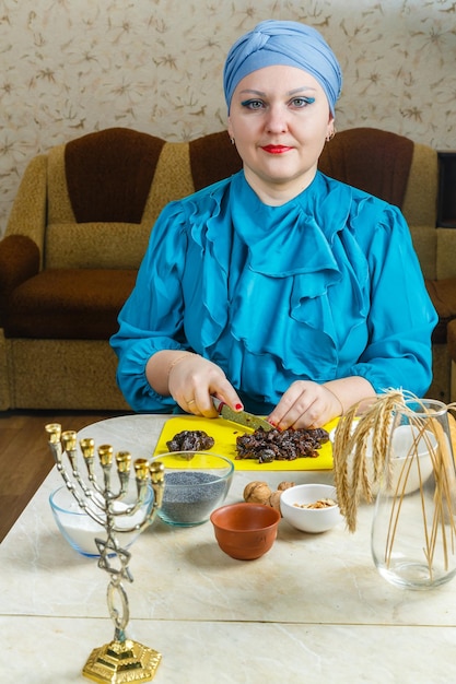 Żydówka w tradycyjnym nakryciu głowy przy stole, przy którym przygotowuje się menora