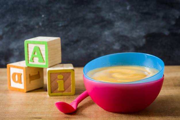 Żywność dla niemowląt: kolorowa miska przecieru owocowego na drewnianym stole