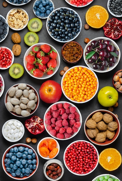 Żywność dla zdrowej diety: jagody, owoce, orzechy, suszone owoce. Czarne tło betonu.